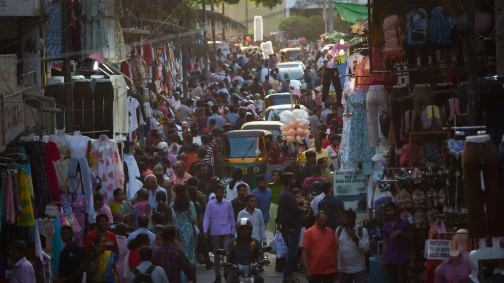 A view of a busy street in India with lots of people and cars.