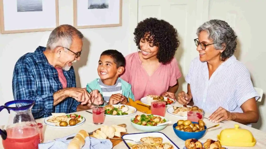A multigenerational family enjoying a meal together at a dining table, smiling and interacting with each other