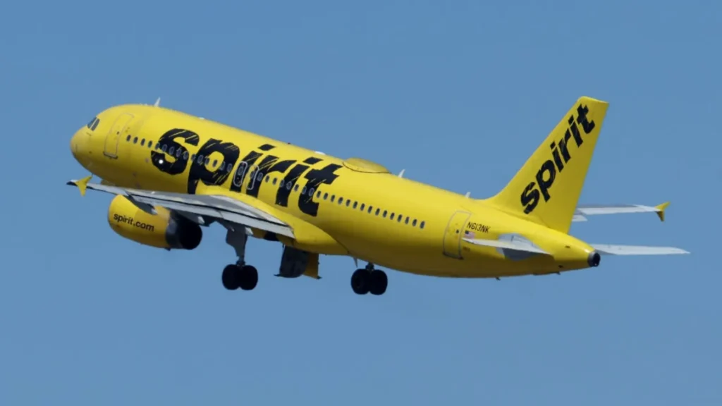 A yellow Spirit Airlines plane taking off against a clear blue sky