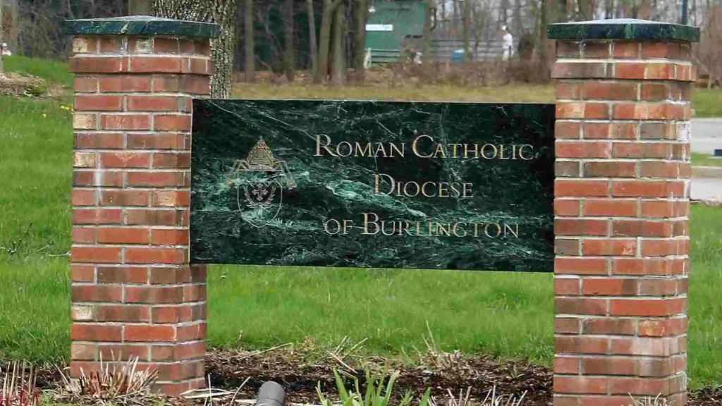 A green and black sign at the entrance of the Roman Catholic Diocese of Burlington