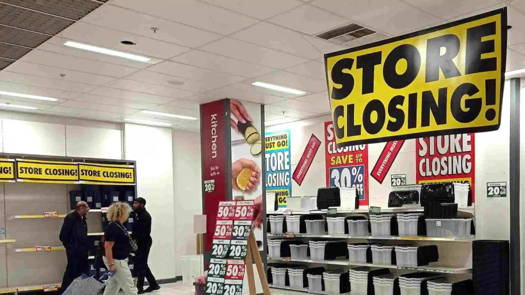 A retail store displaying multiple "Store Closing" signs with various discounts, as customers browse through the remaining merchandise