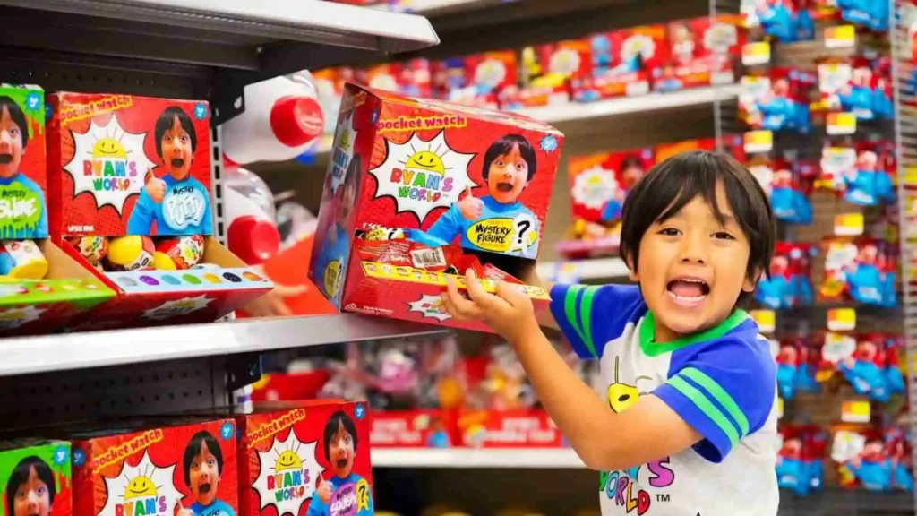 Ryan from Ryan's World, holding a toy from his branded merchandise in a toy store aisle