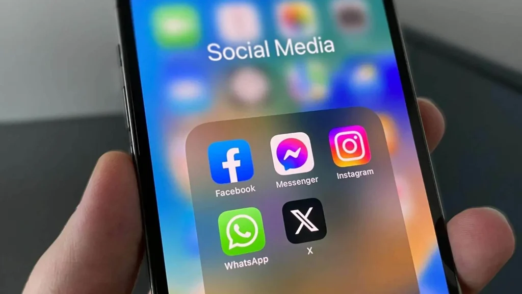 Close-up of a smartphone screen displaying a folder labeled "Social Media" containing app icons for Facebook, Messenger, Instagram, WhatsApp, and X
