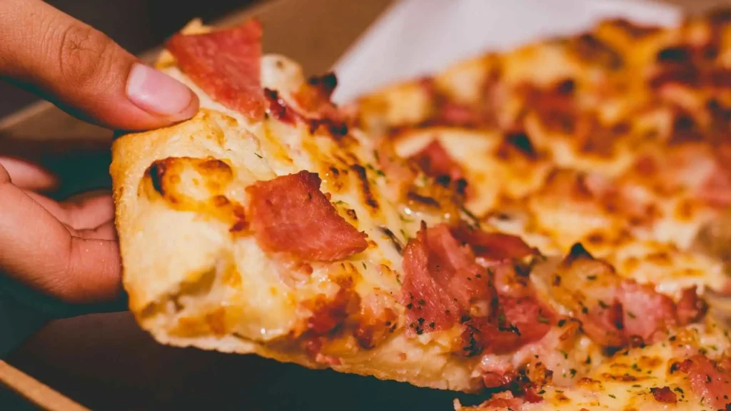 A close-up of a person holding a pizza slice.