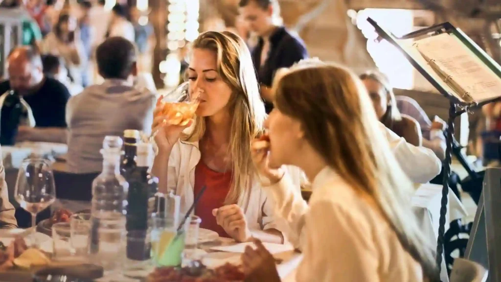 Two women eating and drinking in a restaurant.